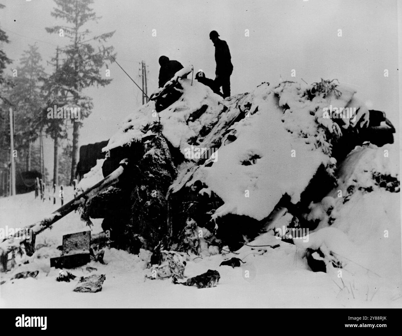 I soldati degli Stati Uniti esaminano il carro armato tedesco coperto di neve fatto esplodere in Belgio -- la fanteria americana della terza divisione corazzata degli Stati Uniti sale sulla cima di un carro tedesco Mark V coperto di neve abbandonato dal nemico quando fu messo al tappeto dalle unità alleate che bloccarono un contrattacco tedesco lanciato in Belgio il 16 dicembre 1944. Con un rapido raggruppamento, il primo e il nono esercito degli Stati Uniti e le forze britanniche attaccarono sul fianco settentrionale del saliente tedesco, mentre il terzo esercito degli Stati Uniti contrattaccò a sud dopo un breve tratto dalla Saar. In 17 giorni, 400 carri armati tedeschi furono distrutti e diverse centinaia Foto Stock