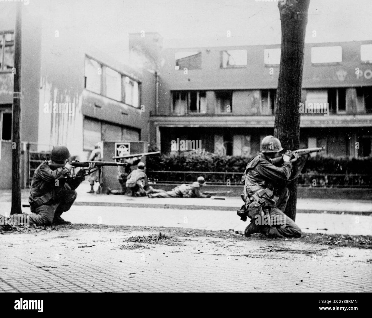 Soldati statunitensi Battle Snipers a Manheim -- fanteria della 44a divisione, settima armata degli Stati Uniti, fuoco contro cecchini nascosti in un edificio a Mannhein, in Germania, durante operazioni di rastrellamento il giorno della sua cattura il 29 marzo 1945. Sul lato opposto della strada, un soldato con una pistola bazooka sta per sparare un razzo nella posizione. La città fu soggetta a bombardamenti e bombardamenti così pesanti che difficilmente un edificio rimase intatto. Mannheim si trova sul fiume Reno, 35 miglia a sud di Magonza. 10 maggio 1945. (Foto di Richard Boyer, U.S. Office War Information). Foto Stock