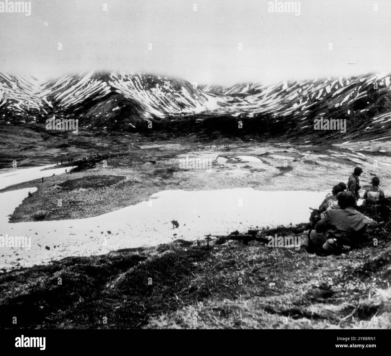 Questa è la guerra come combattuto su Attu -- attraverso questa valle su Attu ***** Sopra la nebbia che oscura le cime delle montagne si trovano i passi che conducono a Holtz Bay e Chichagof Bay, basi dell'isola Jap Attu che devono essere catturate. Nella valle al centro della destra, tornando indietro verso le montagne, ci sono forti posizioni Jap. Quei punti sparsi sul fondovalle sono truppe statunitensi che avanzano sotto il fuoco per allontanare i giapponesi. Sulla destra c'è la posizione della pistola statunitense. 6 luglio 1943. (Foto di AP Wirephoto). Foto Stock