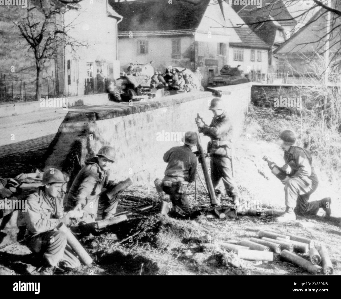 Seventh Army Yanks Shell Germany -- Un equipaggio di mortai del Settimo esercito americano pompa proiettili in Germania da una posizione appena fuori dalla strada principale della città di confine ALSAZIANO-tedesca di LAUTERBIURG.da sinistra a destra sono: PFC EUGEN GILES, ITHACA, N.Y.; Pvt. JOSEPH BARTANUS, AVELLA, PA.; CPL GEORGE CARLISLE, HENDERSON, N.C.; PA.DICEMBRE 27, 1944. (Foto di AP Wirephoto). Foto Stock