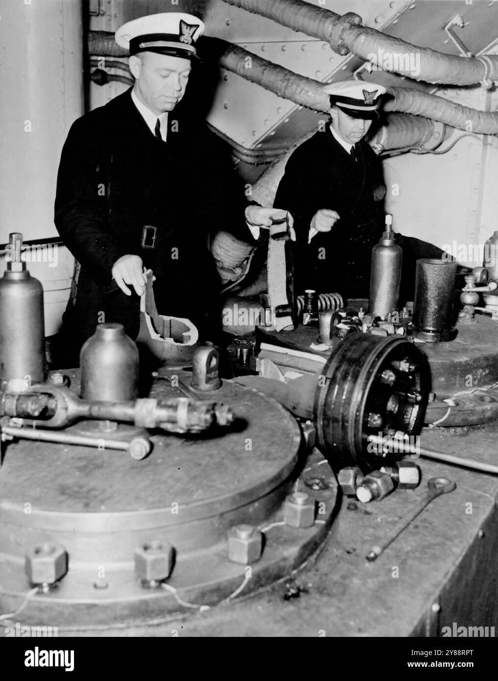 Gli equipaggi sabotano le navi italiane qui - due ufficiali della Guardia Costiera ispezionano i danni alle teste dei cilindri dei motori della 6.100-Ton S.S. Alberto che si ritiene siano stati fatti dall'equipaggio italiano. Venticinque guardiani costieri e doganieri hanno preso qui oggi cinque navi italiane in seguito agli ordini del governo di mettere tutte le navi mercantili italiane nelle acque territoriali statunitensi sotto custodia protettiva per salvaguardare gli americani. 30 marzo 1941. (Foto di ACME). Foto Stock