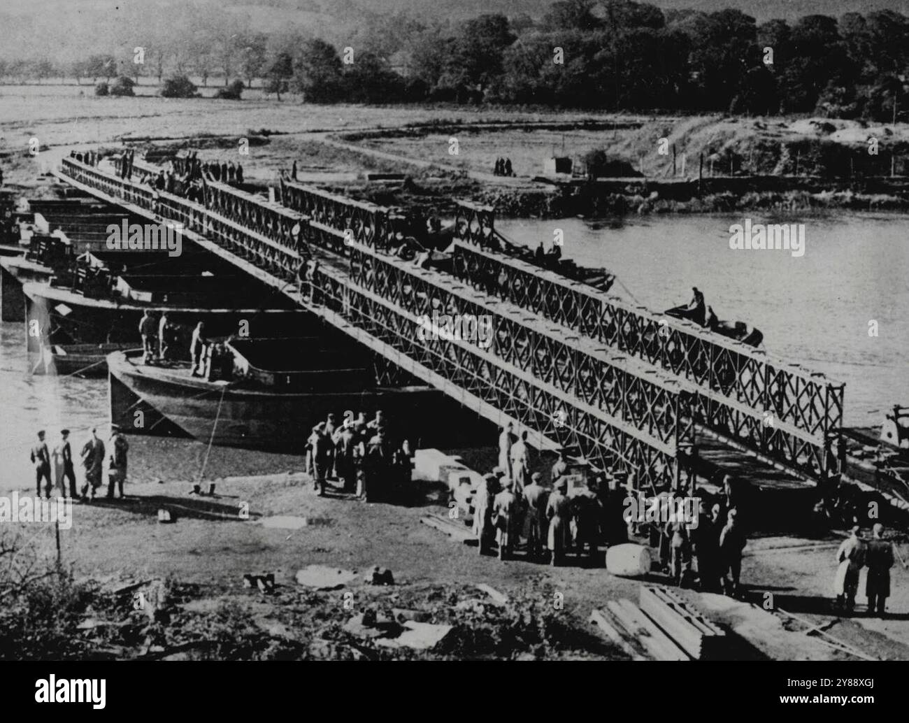 Allied Portable Bridge accelera l'inseguimento del nemico -- Un ponte "Bailey", inventato da Donald Coleman Bailey, del Ministero britannico delle forniture, è testato in Inghilterra. Prodotto negli Stati Uniti e in Gran Bretagna, viene utilizzato dagli Alleati per sostituire rapidamente le strutture distrutte dal nemico in ritirata o dai bombardamenti alleati. Sei soldati possono assemblare le sezioni di tre metri che vengono spinte sui rulli per coprire una distanza. Nella sua forma più leggera, un'estensione di 240 piedi (72 metri) può sopportare un carico di 20 tonnellate. Con i pontoni il suo allungamento è quasi illimitato e la sua forza, come la sua lunghezza, può essere raddoppiata o triplicata a m. Foto Stock