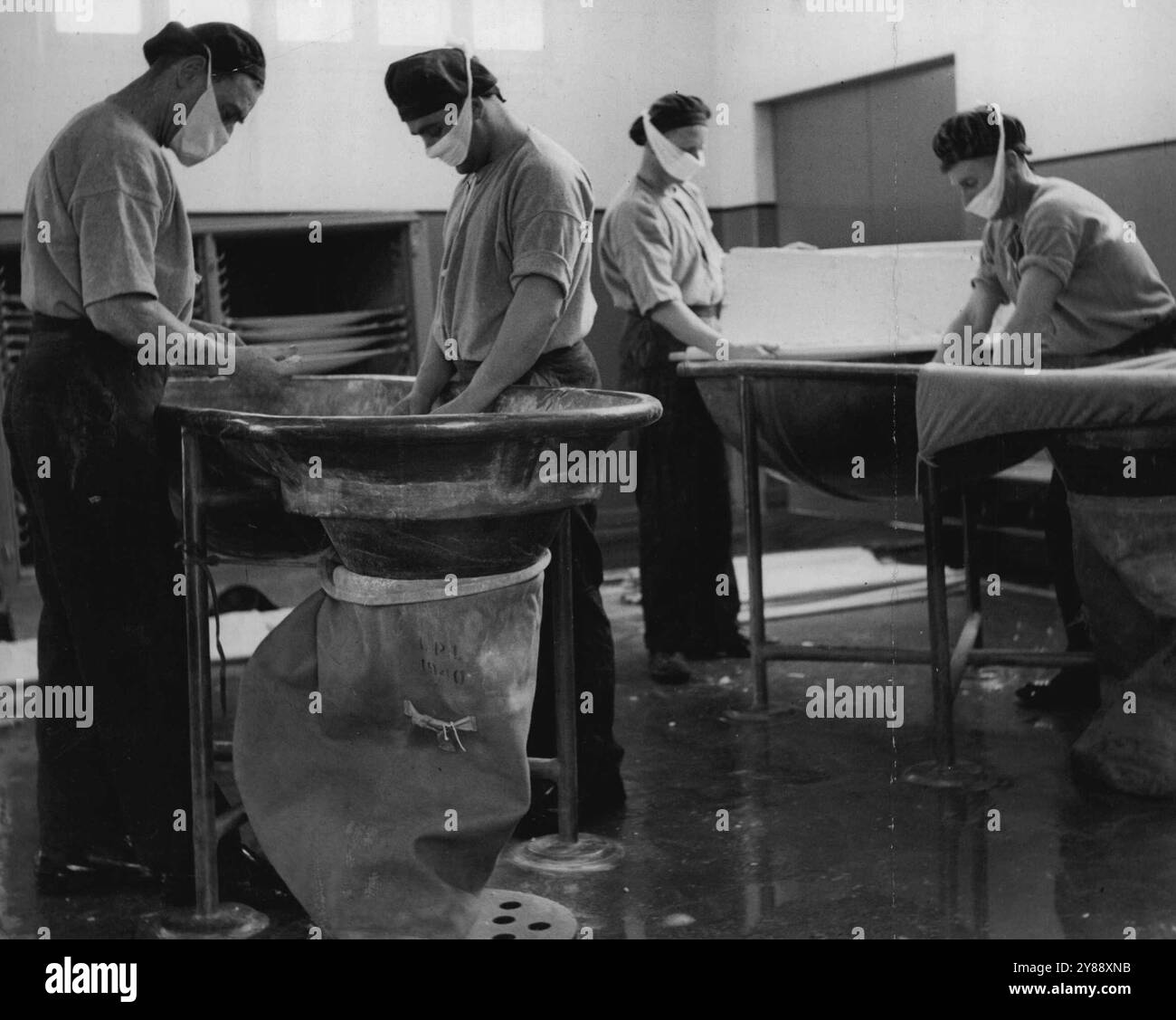 La miscela di cotone e nitroglicerina, pressata in fogli e essiccata, va al locale di sbriciolamento della pasta, dove viene accuratamente spezzata a mano in bagni di piombo. Quindi passa attraverso uno schermo grezzo, in sacchetti, pronti per il processo successivo. La cordata, il propellente standard per fucili e pistole britanniche, è il risultato di una miscela appositamente preparata di cannone e nitroglicerina, generalmente sotto forma di sottili bastoncini o corde color miele. Cordite viene prodotta su larga scala in questo stabilimento di Melbourne. 8 novembre 1950. Foto Stock