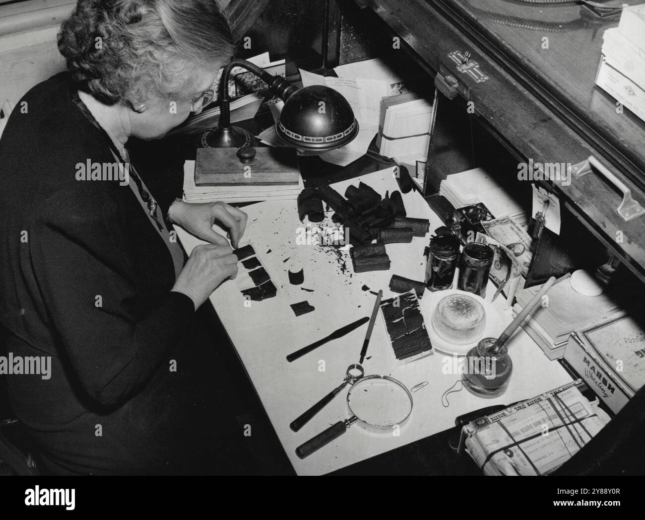 Soldi da bruciare - ricostruzione finanziaria... La signora Bertha S. Walker, dipendente della Divisione Redemption del Bureau of Printing and Engraving, sta lavorando a un caso di denaro bruciato. E' a capo della sezione dei soldi mutilati. Due piccole lattine sono state inviate al suo dipartimento con una dichiarazione che una conteneva 600 dollari e l'altra 75 dollari. La signora Walker smista i frammenti e incolla le singole bollette. Se è possibile trovare l'importo giusto, l'intero importo verrà riscattato nella nuova valuta. Devono essere presentati tre quinti di un disegno di legge per ottenere il pieno valore; chiaramente oltre i due quinti per metà valore. Meno di due pugni Foto Stock