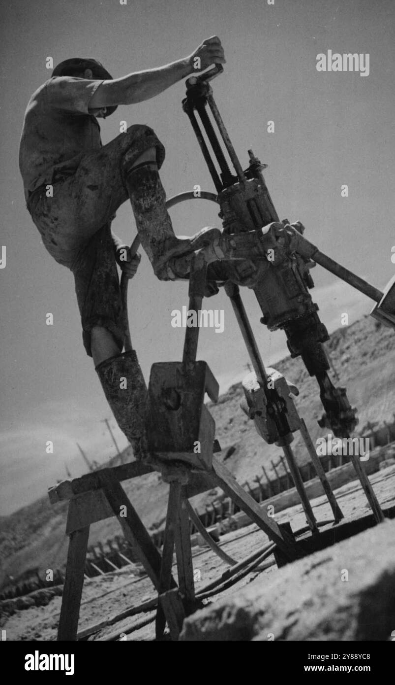 Come preliminare per le operazioni di brillamento su un progetto del Consiglio di lavoro alleato, questo C.C.C. MAN gestisce una perforatrice da roccia. 22 giugno 1943. (Foto di Allied Works Council). Foto Stock