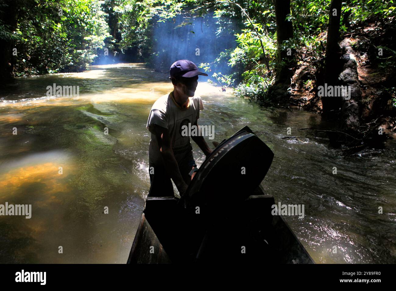 Un automobilista che spinge la barca a muoversi in acque poco profonde nel fiume, attraverso la foresta abituale di Dayak IBAN nel Kalimantan Occidentale, Indonesia. Foto Stock