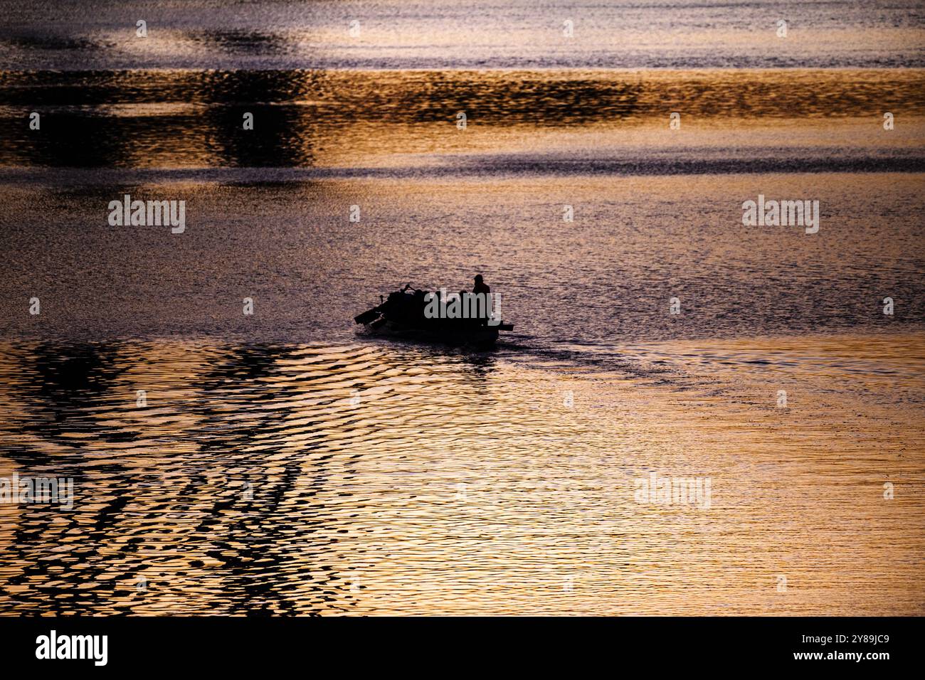 Silhuette di persone che regnano sulla barca nel Victoria Harbour al tramonto con un grazioso colore del tramonto che si ripete sulla superficie dell'acqua a Melbourne, Victoria, Australia Foto Stock