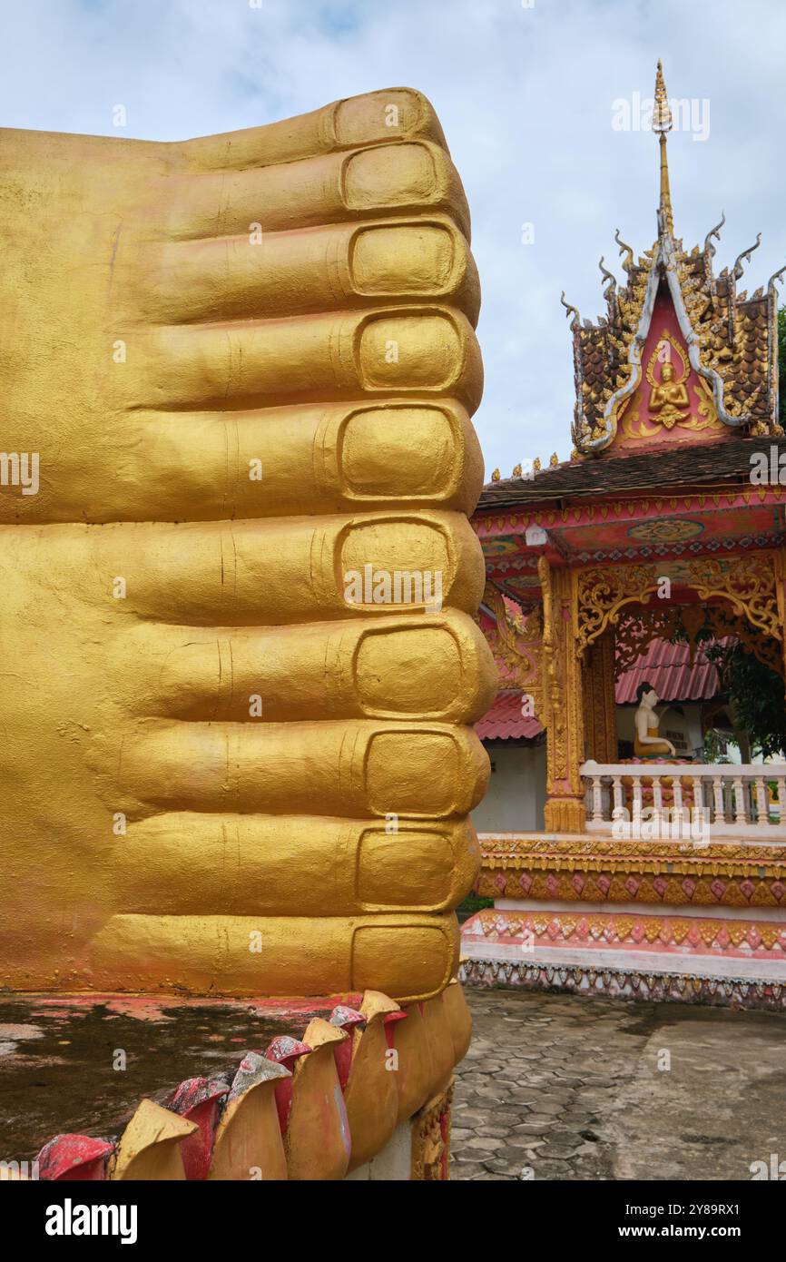 Grande, esterno, dipinto, oro, reclinabile, rilassante statua di Buddha addormentata, scultura, figura in una giornata nuvolosa. A Wat That Khao a Vientiane, Laos Foto Stock