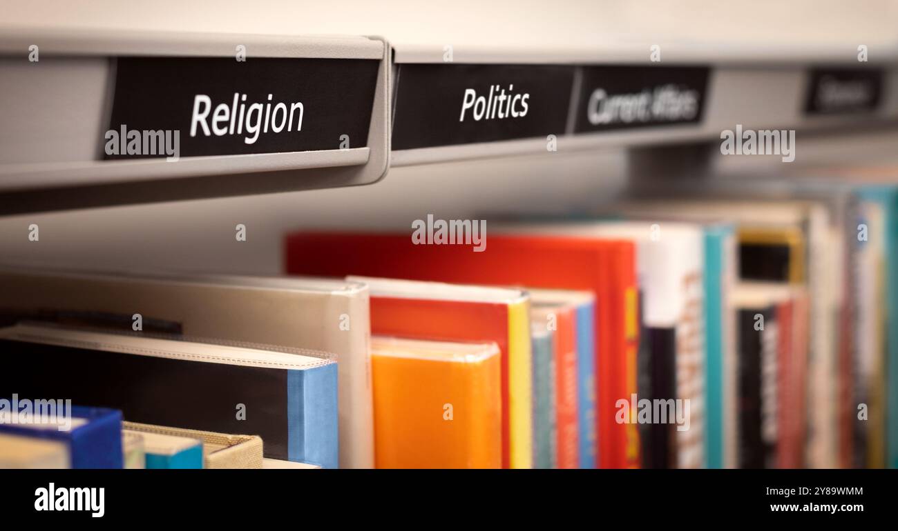 Libri impilati sugli scaffali sotto categorie di religione e politica. Una biblioteca di saggistica o una scena di libreria che raffigura una fila di libri di riferimento fattuali. Foto Stock