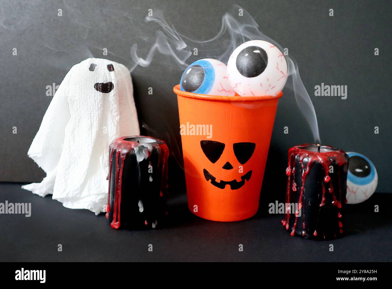 Set di diversi elementi di Halloween fatti a mano su sfondo nero. Jack o lanterna riempita di occhi. Fantasma. Candele nere cosparse di gocce rosse. Foto Stock