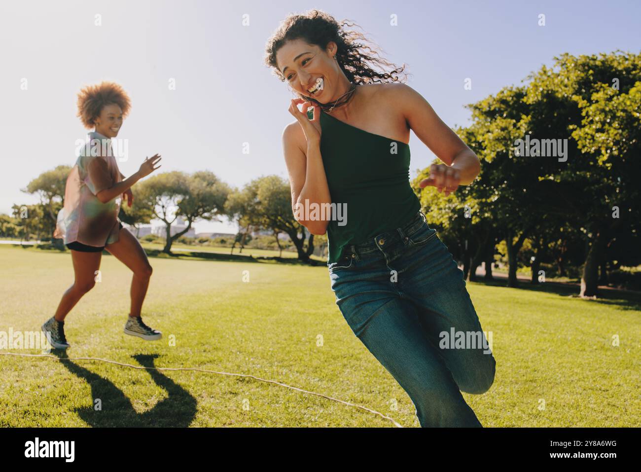 Due giovani donne impegnate in attività all'aperto dinamiche e divertenti, godendosi la libertà di una giornata di sole nel parco. Momenti vivaci e gioiosi catturati. Foto Stock