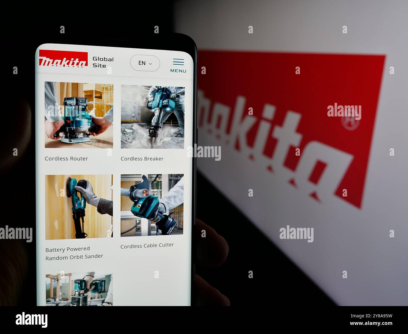 Persona che tiene lo smartphone con la pagina Web dell'azienda giapponese Makita Corporation sullo schermo con il logo. Messa a fuoco al centro del display del telefono. Foto Stock