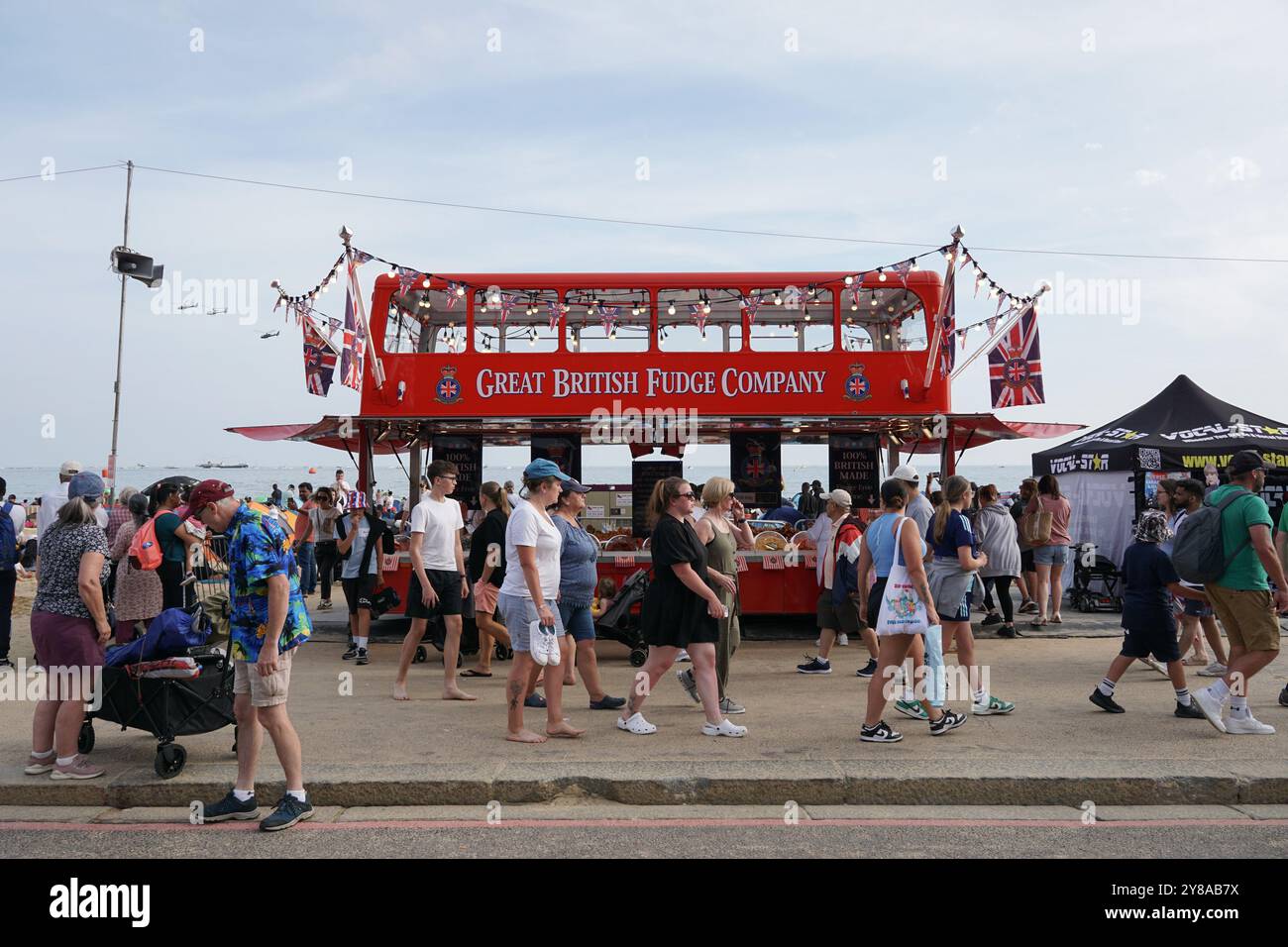 Folle di persone che passano davanti all'autobus della Great British Fudge Company sulla spiaggia di Bournemouth durante l'annuale spettacolo aereo del 29 agosto 2024. Eventi inglesi sul mare Foto Stock