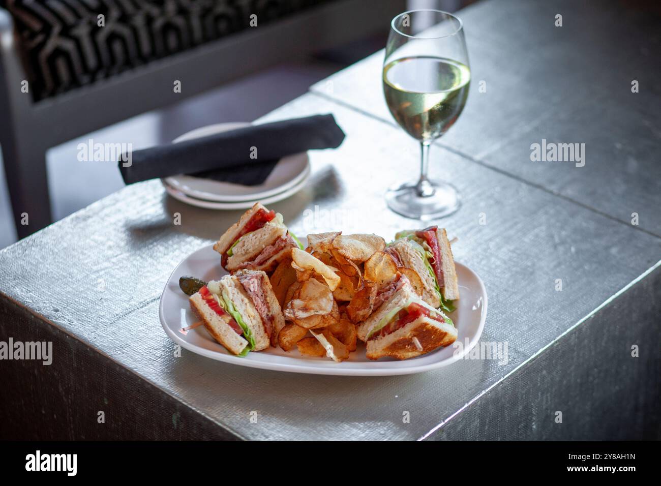 Ampia vista del club sandwich sul piatto con patatine e un bicchiere di vino Foto Stock