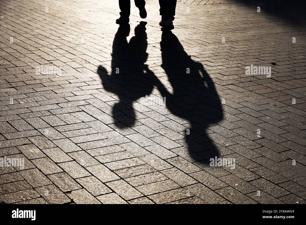 Sagome di due persone che camminano lungo la strada. Ombre di adulti e bambini sul marciapiede Foto Stock