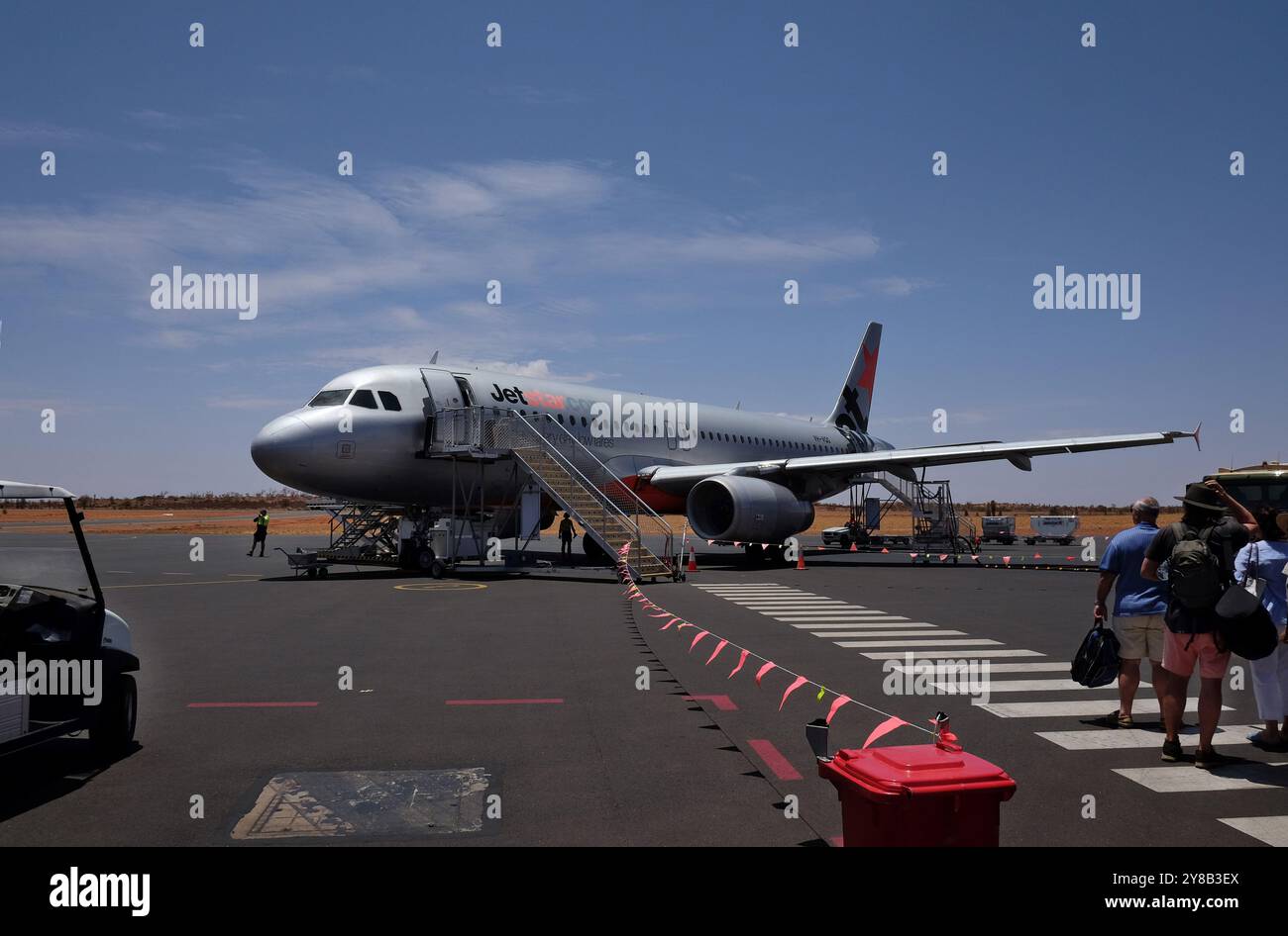 Un aereo Jetstar Airbus che sale a bordo dei passeggeri che attraversano l'asfalto all'aeroporto di Ayers Rock (Aeroporto Connellan) a Yulara, Uluru, Australia centrale Foto Stock