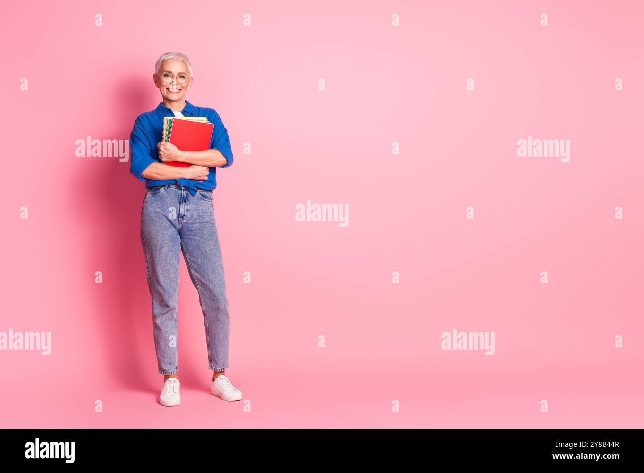 Foto a tutta lunghezza di una camicia blu elegante e lucente che regge diari spazio vuoto sfondo rosa isolato Foto Stock