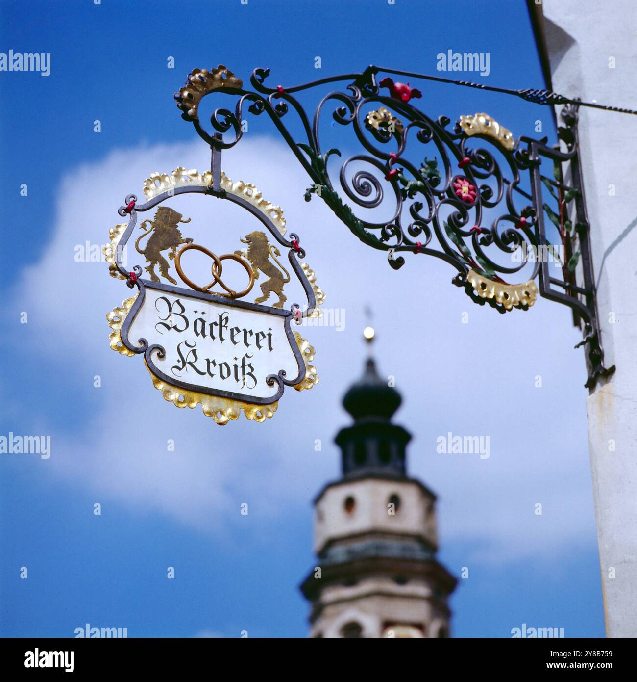 DAS allte Zunftsschild der Bäckerei Kroiß in Tittmoning mit dem Kirchturm der St. Laurentius Pfarrkirche im hintergrund, Bayern um 1984. 90020000160 Foto Stock