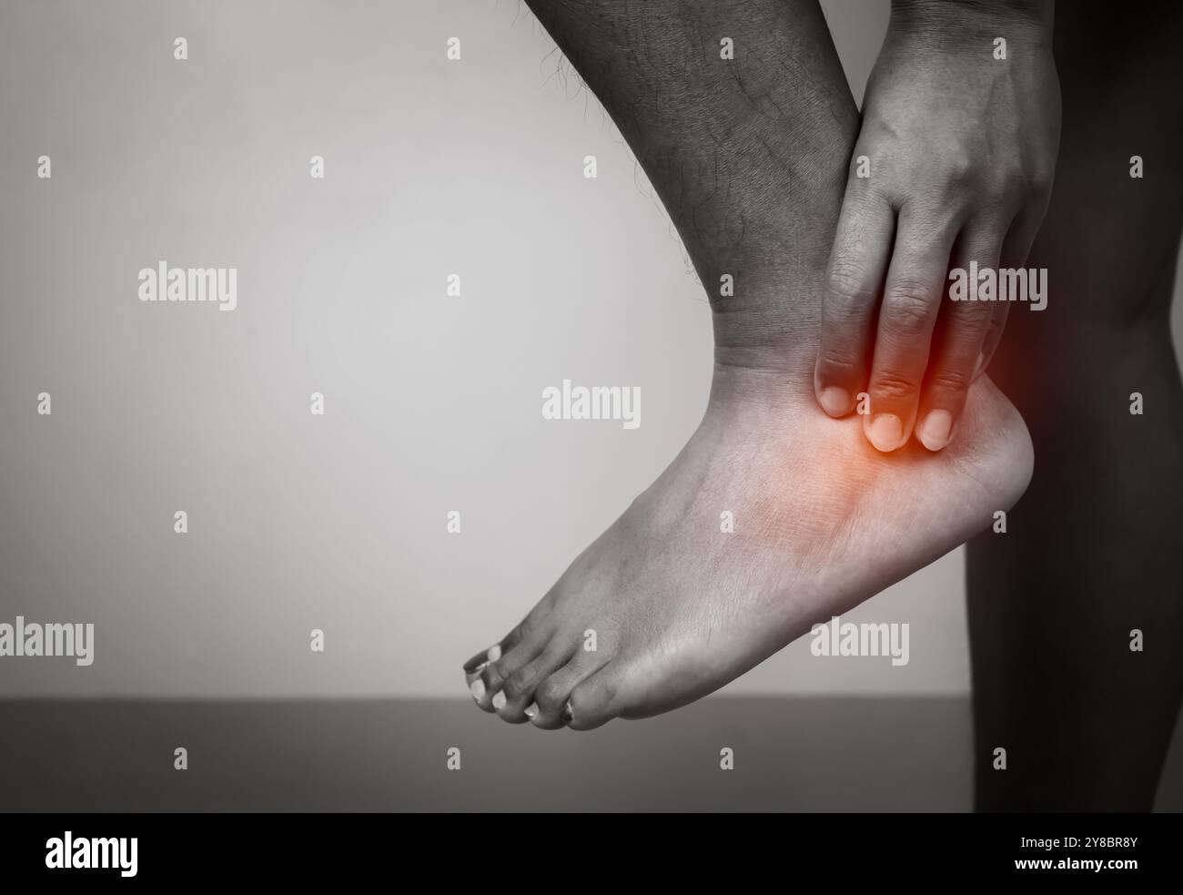 Donna con dolore acuto caviglia con dolore alle gambe su sfondo grigio, caviglia e trattamento delle gambe, donna massaggiante il suo spasmo muscolare caviglia, assistenza sanitaria e medico Foto Stock