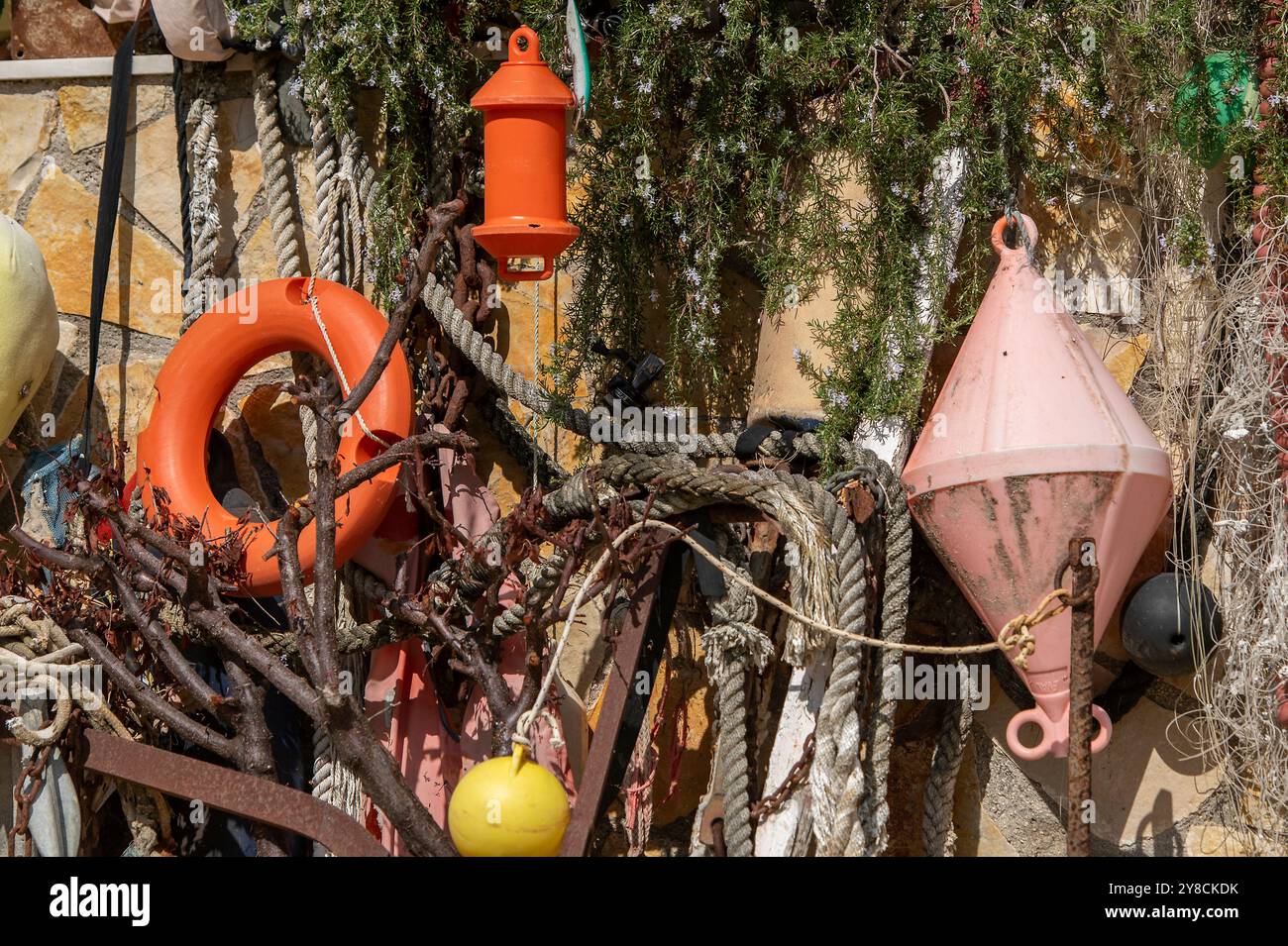 una selezione casuale di oggetti marini, marittimi e nautici, tra cui reti, galleggianti, anelli di salvataggio e corde esposti insieme davanti a una casa. Foto Stock