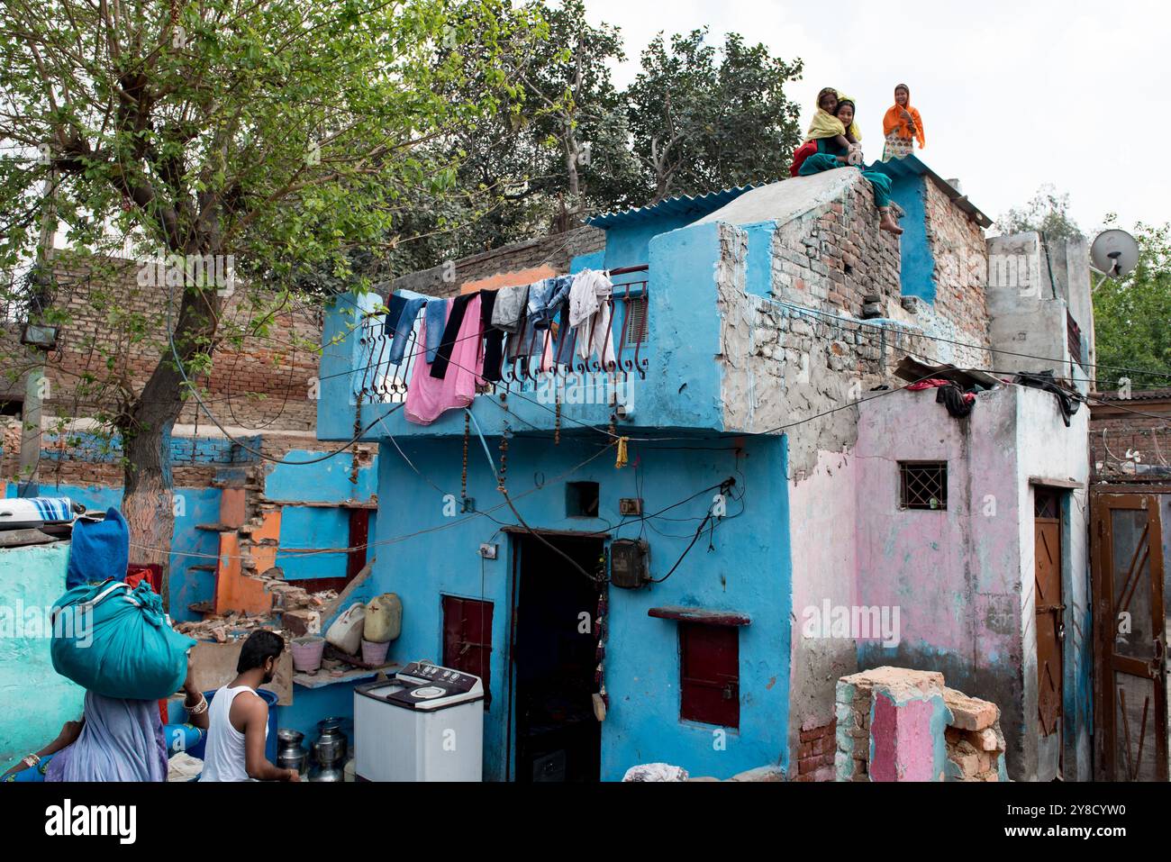 Nuova Delhi, India, 11 marzo 2017: Le persone stanno vivendo la loro vita quotidiana di fronte alla loro casa blu. Slum di nuova delhi, India Foto Stock