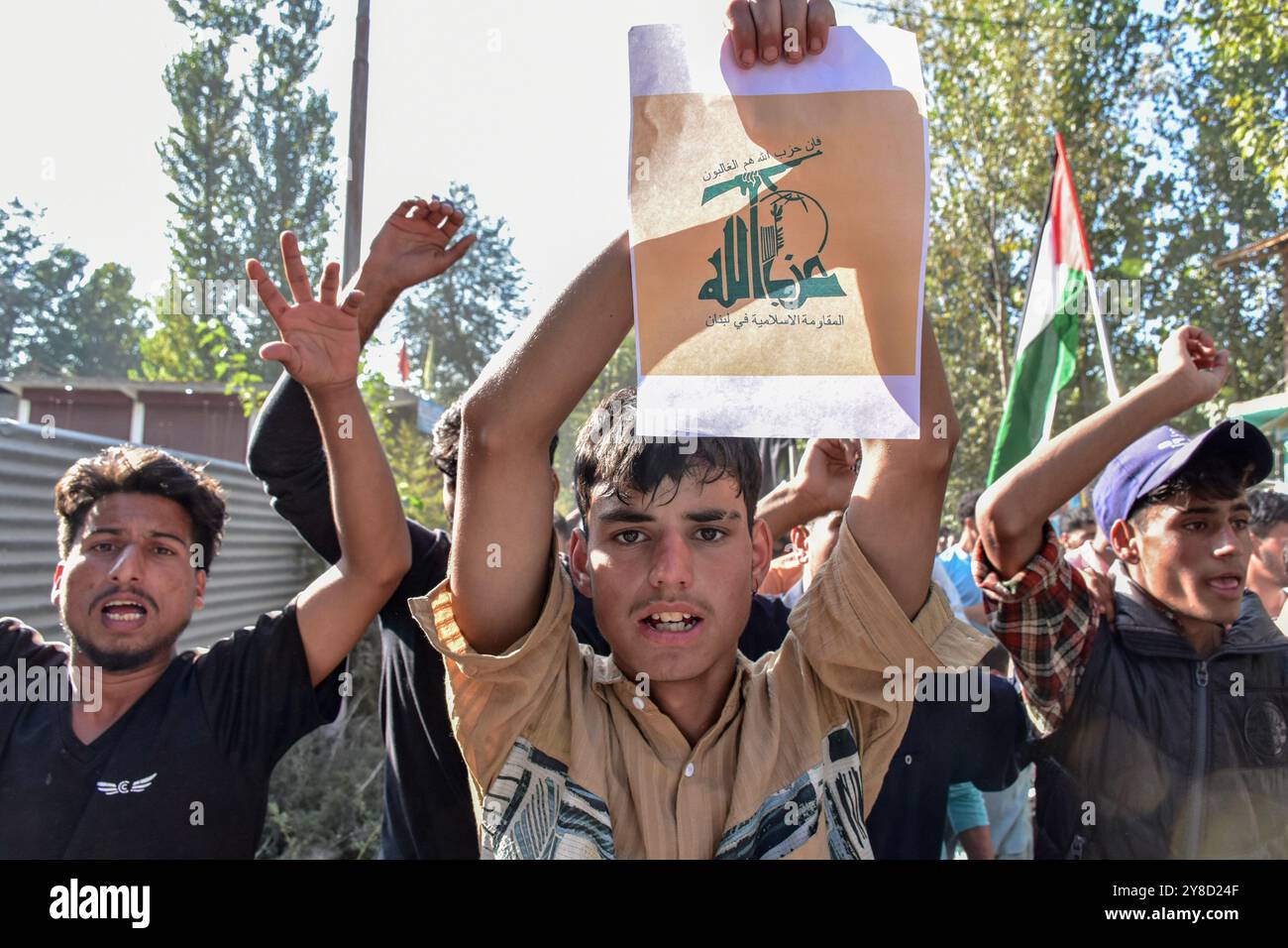 Kashmir, India. 4 ottobre 2024. Un musulmano sciita del Kashmir ha un manifesto della bandiera di Hezbollah, mentre altri gridano slogan pro-Palestina e anti-Israele durante una protesta in solidarietà con la Palestina e contro l'uccisione del leader di Hezbollah Hassan Nasrallah, a Pattan, a 30 km da Srinagar, la capitale estiva di Jammu e Kashmir. Credito: SOPA Images Limited/Alamy Live News Foto Stock