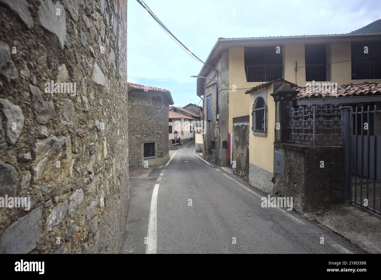 Strada stretta delimitata da case in una città in montagna in una giornata nuvolosa Foto Stock