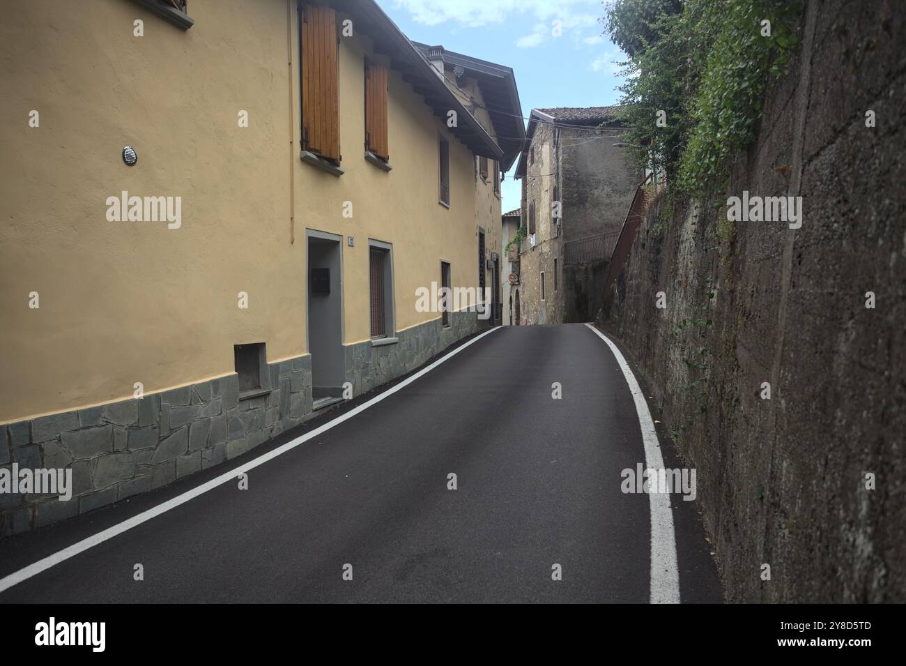 Strada stretta delimitata da case in una città in montagna in una giornata nuvolosa Foto Stock