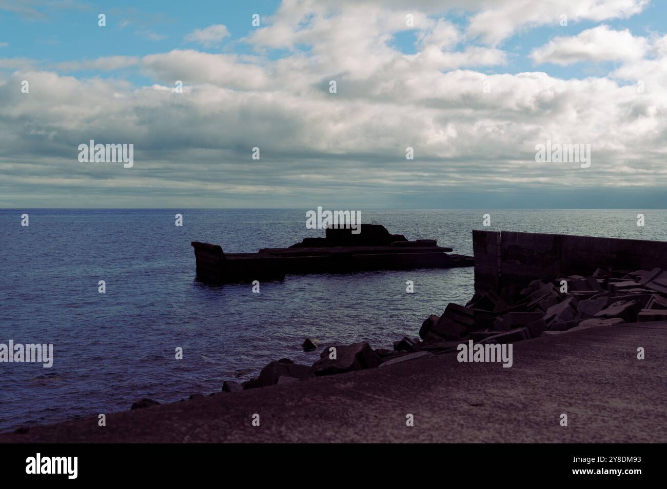 Calme acque oceaniche e un molo solitario sotto un cielo nuvoloso a Madeira Foto Stock