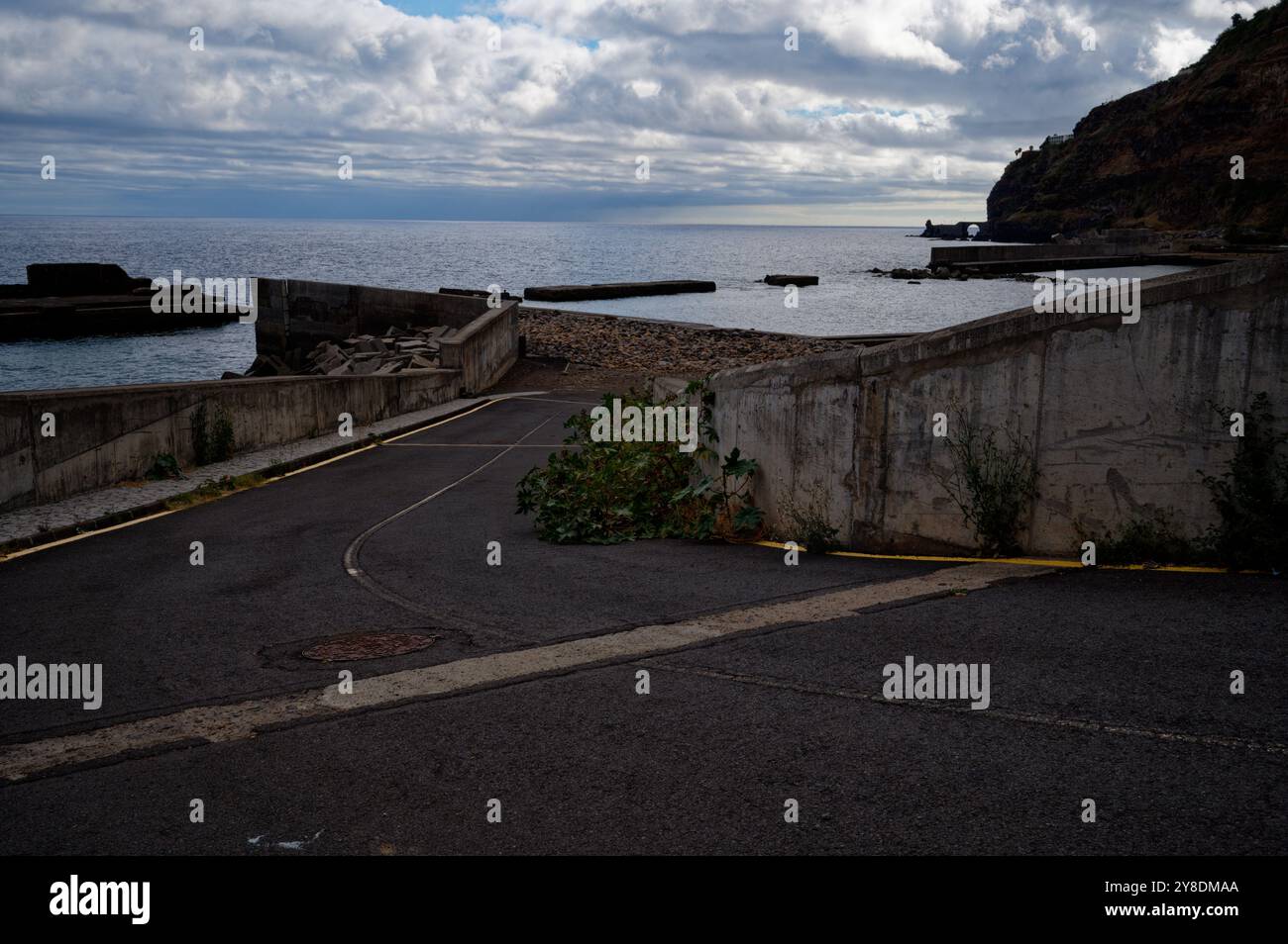 Strada costiera deserta che conduce al mare sotto un cielo nuvoloso a madeira Foto Stock
