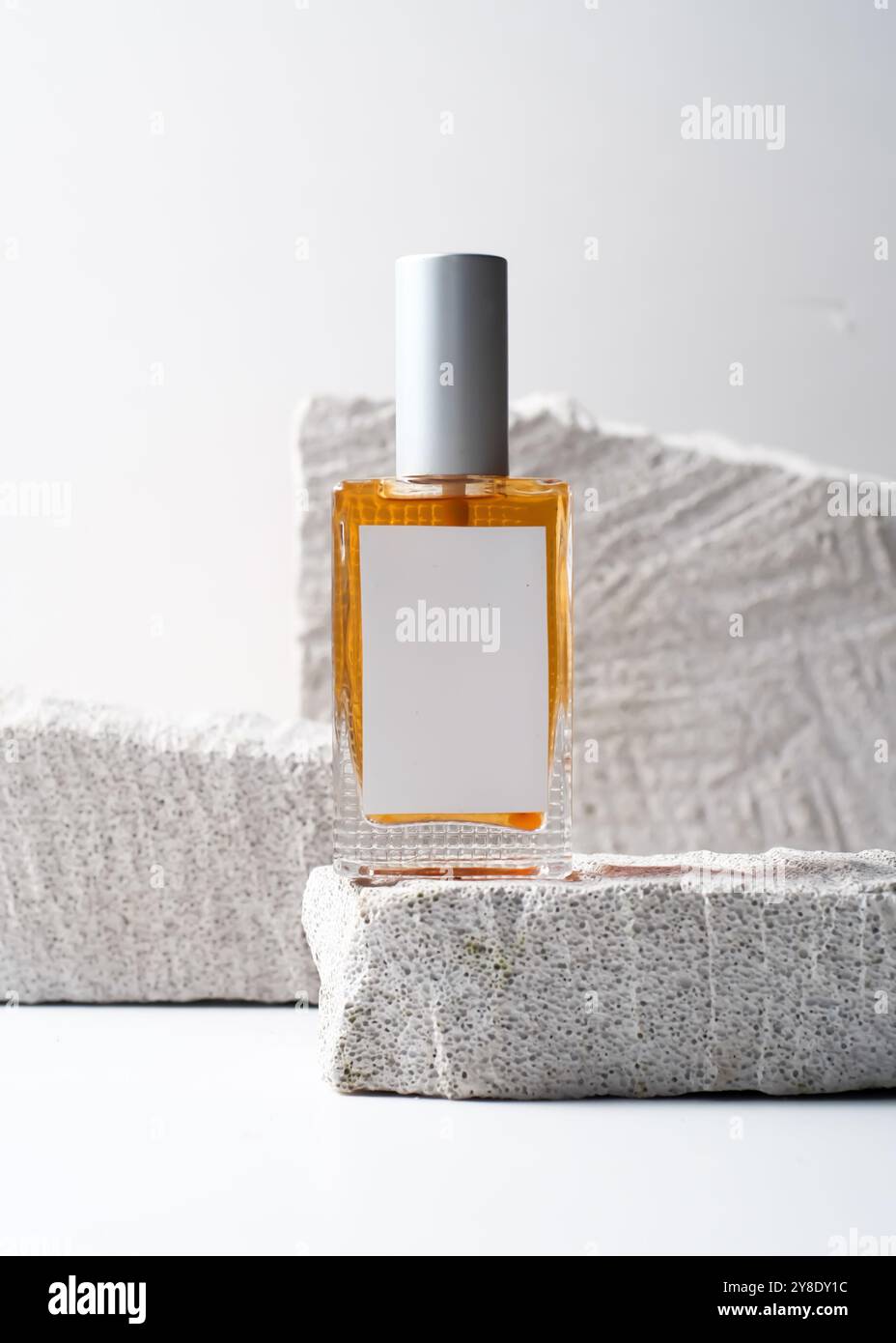 Un modello di bottiglia di profumo con un'etichetta bianca pulita, su uno sfondo in pietra bianca in uno stile fotografico minimalista e moderno. Questa immagine è ide Foto Stock