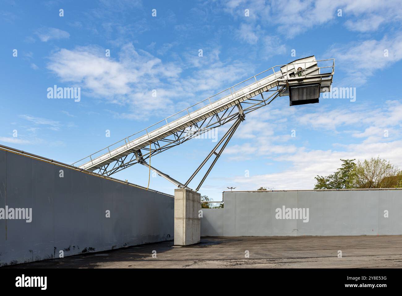 Il nastro trasportatore di grandi dimensioni si estende su una parete, in contrasto con il cielo blu Foto Stock