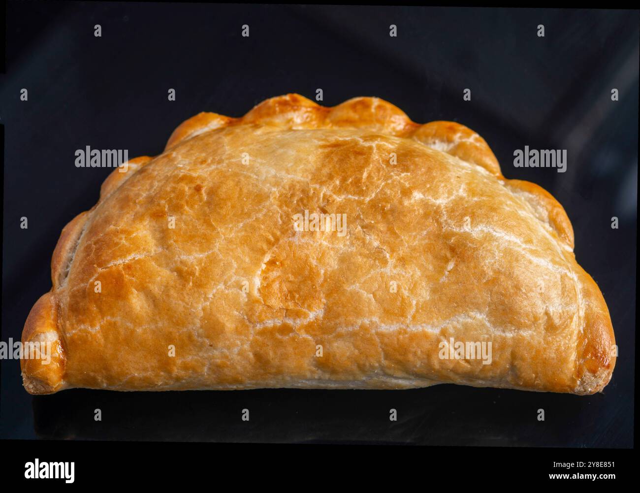 Primo piano della pasticceria dello spuntino fresco e pastoso, pronto da preparare e mangiare, semplicemente posizionato, isolato su una superficie nera lucida, prima di tagliare o aggiungere Foto Stock