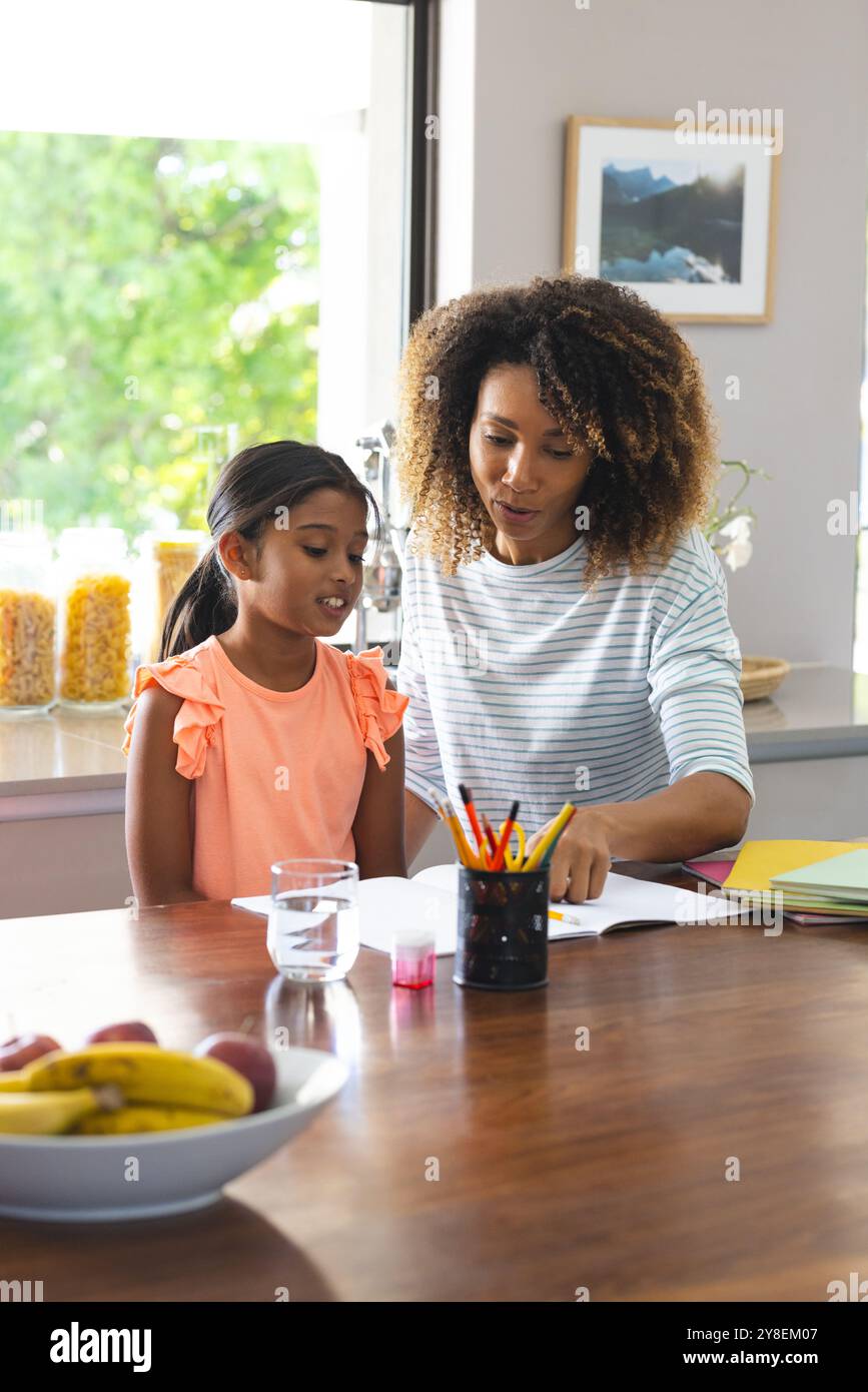 Madre birazziale aiuta una figlia birazziale con i compiti a casa Foto Stock