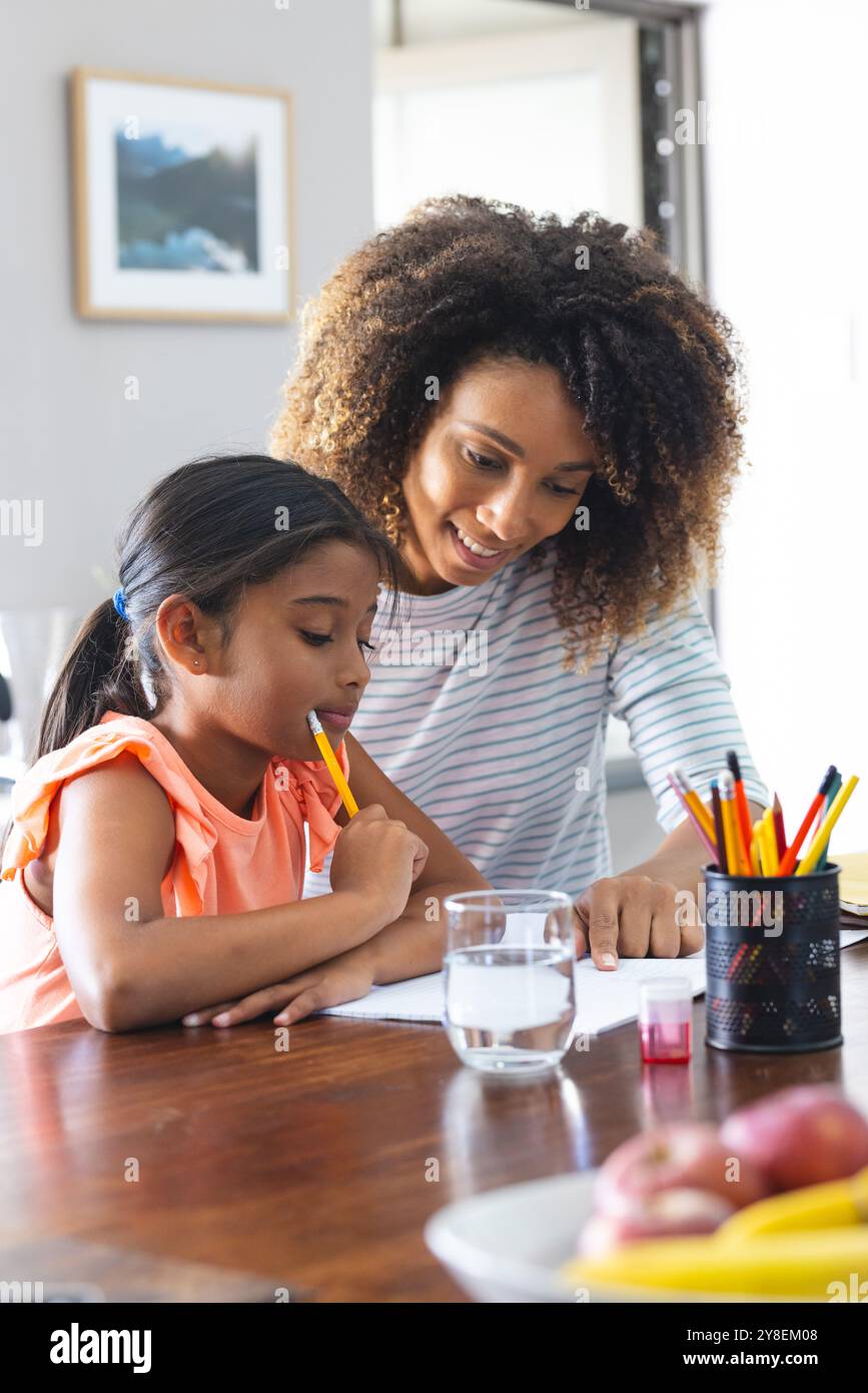 La donna birazziale aiuta sua figlia con i compiti a casa Foto Stock