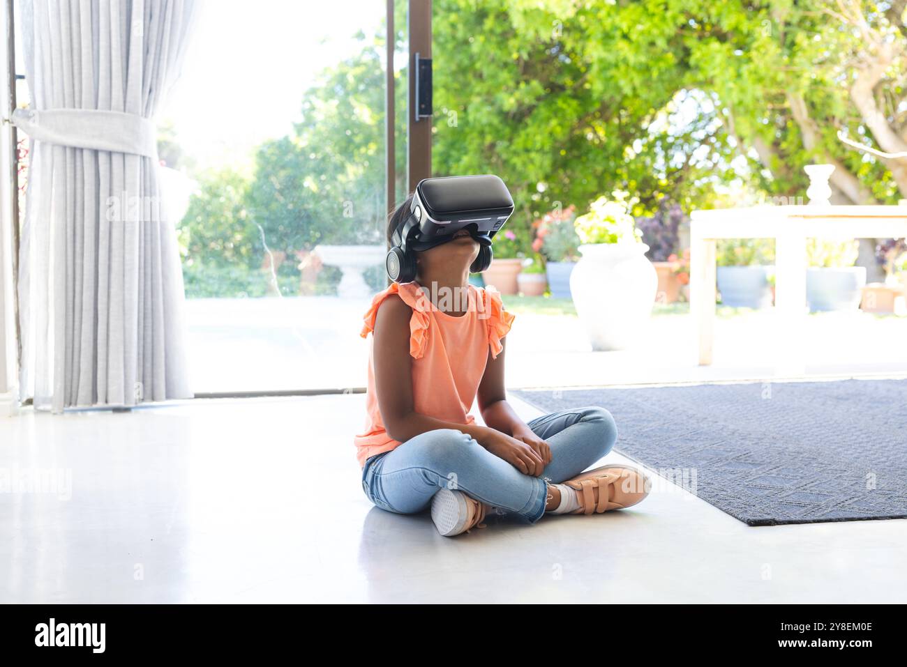 La ragazza birazziale esplora la realtà virtuale a casa Foto Stock