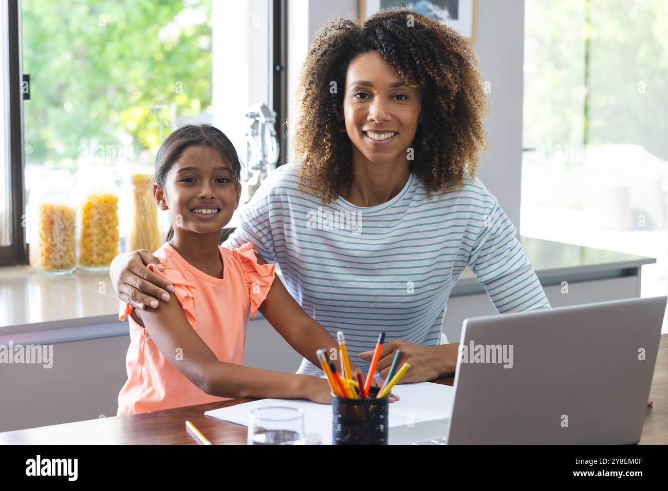 Madre e figlia birazziali sorridono a casa Foto Stock