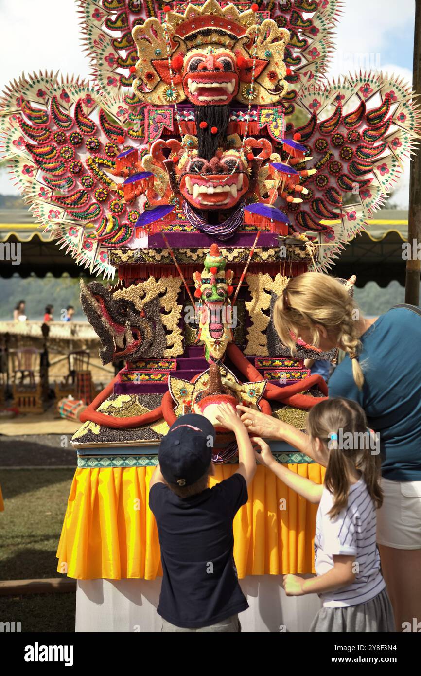 Donne e bambini turisti che prestano attenzione a un'arte scultorea tradizionale fatta di farina di riso (offerta per cerimonia spirituale) a Bali, Indonesia. Foto Stock