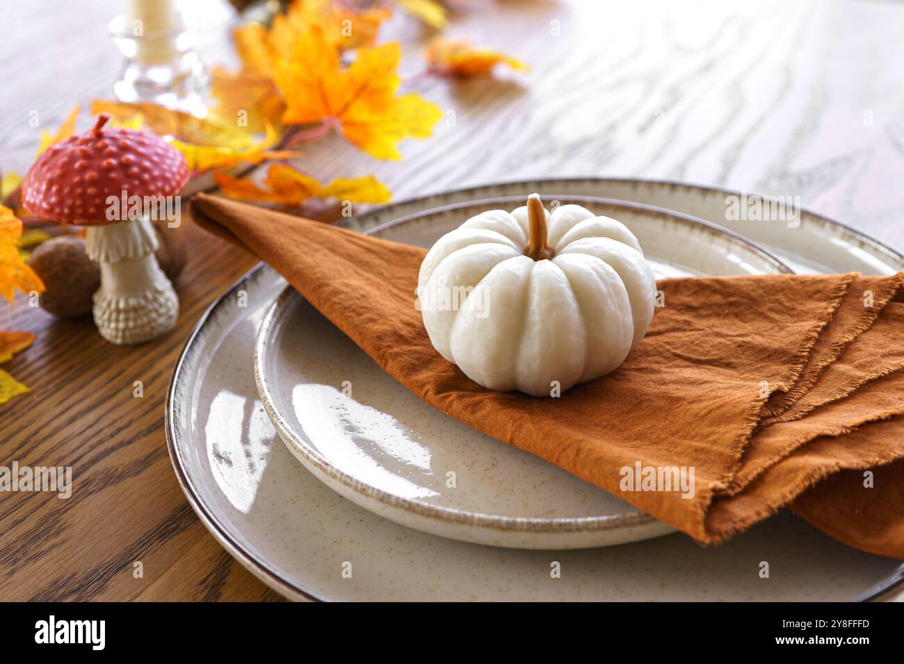 Autunno, autunno, Halloween o festa del Ringraziamento. Foglie cadute, zucche e tovagliolo sul piatto su sfondo di legno. Foto Stock
