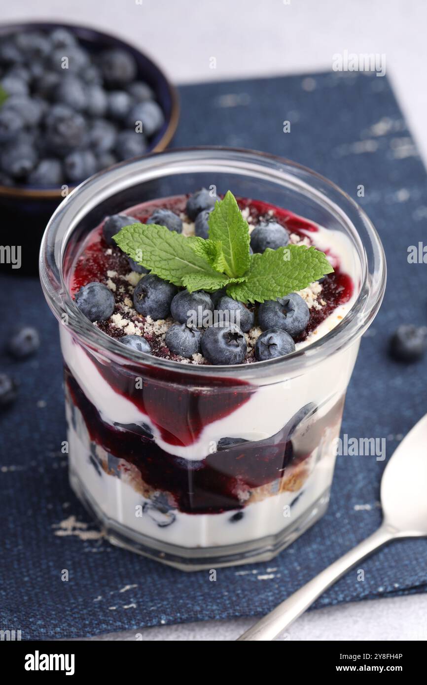 Gustoso dessert trifle. Mirtilli, pan di Spagna e panna montata in vetro su un tavolo grigio chiaro Foto Stock