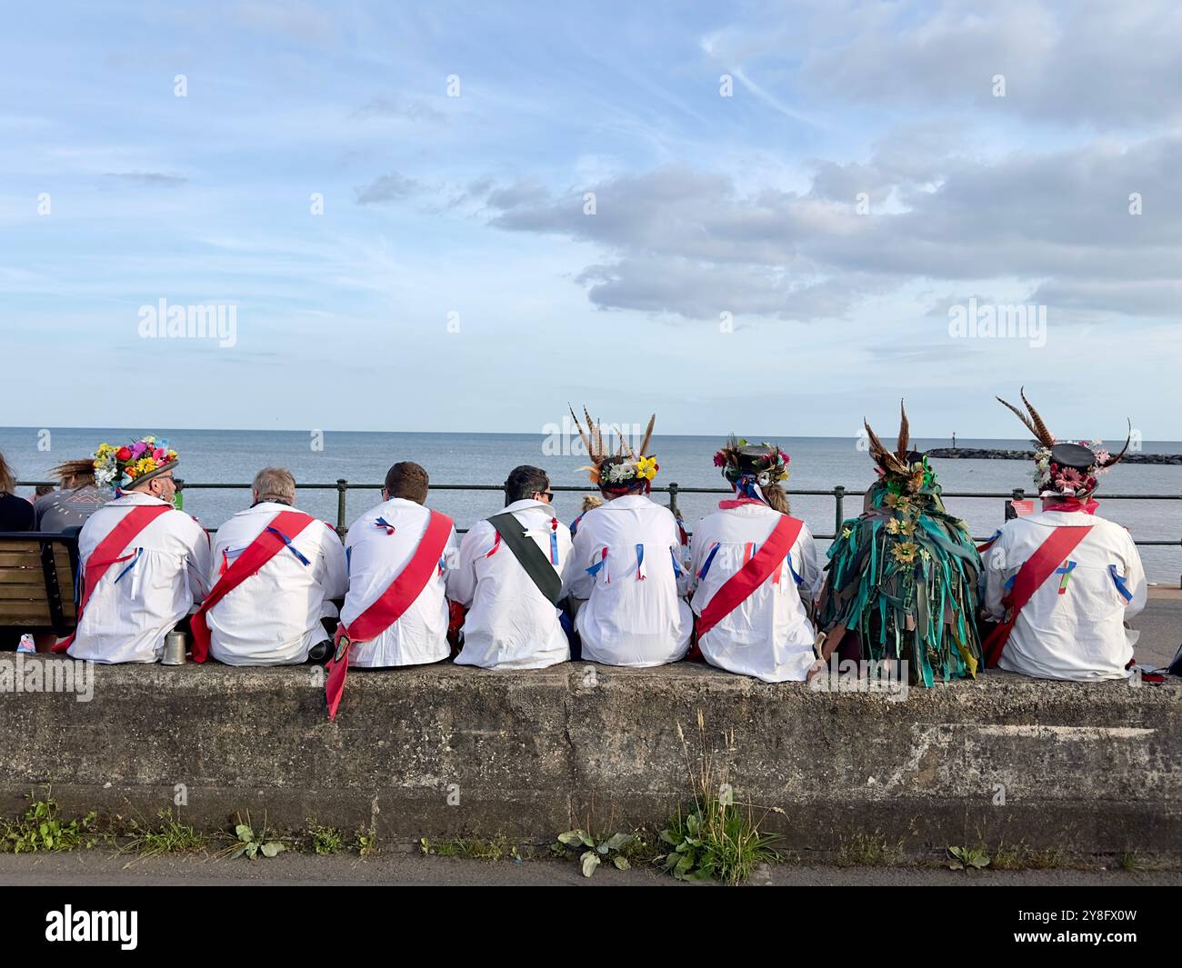 Squadra di ballo Morris che riposa sul lungomare, Sidmouth folk festival, Sidmouth, Devon, Regno Unito - Immagine stock catturata con smartphone