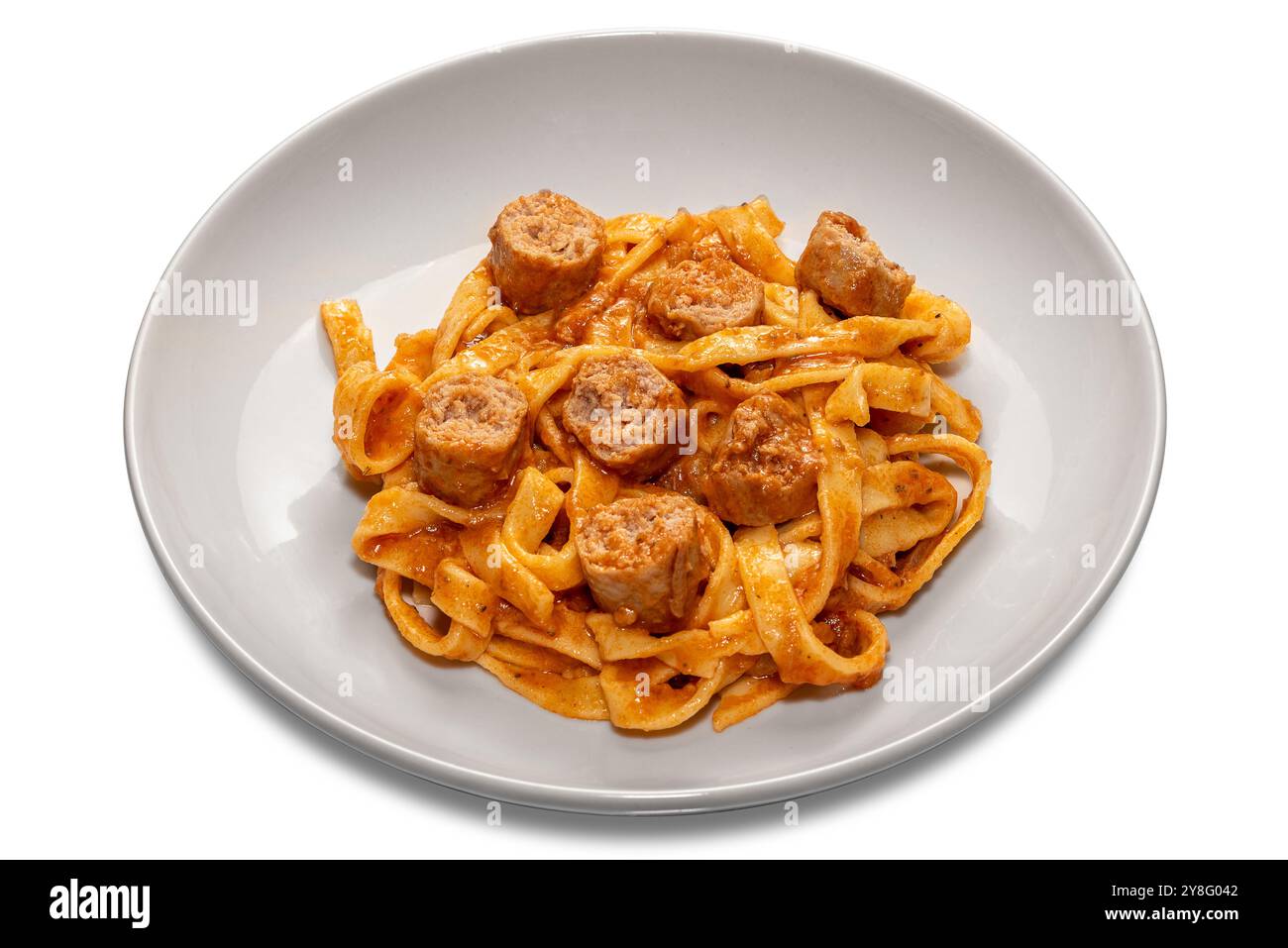 Tagliatelle di pasta all'uovo con salsa di pomodoro rosso con pezzi di salsiccia in piatto bianco isolato su bianco con percorso di taglio incluso Foto Stock