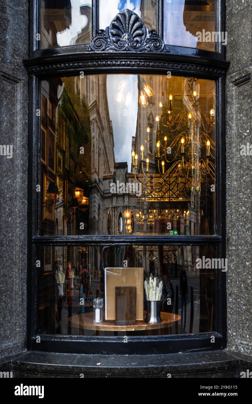 Uno spazio interno con un enorme lampadario. Nella finestra, vedrai una splendida riflessione di antichi edifici in un classico stile europeo Foto Stock