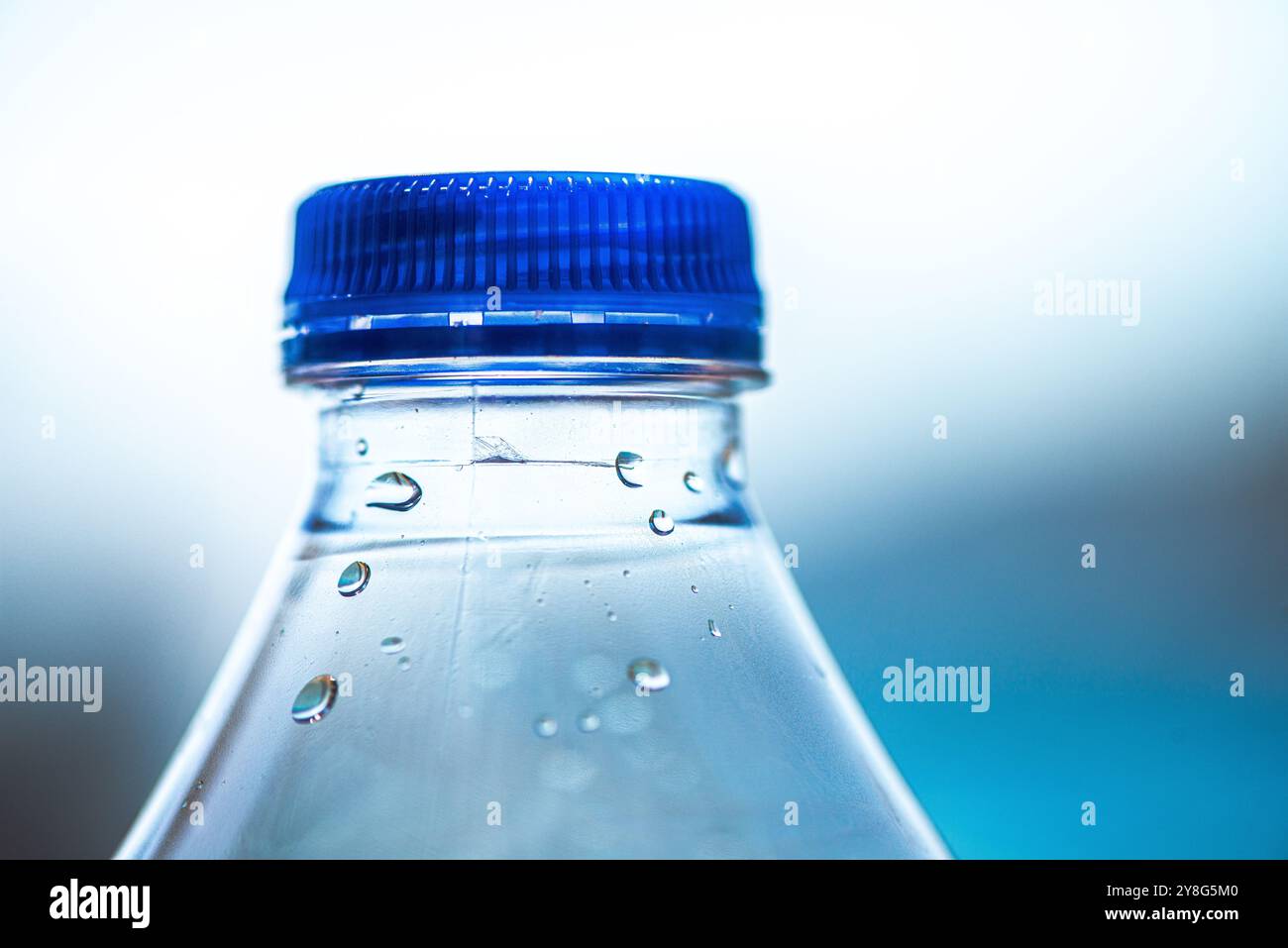 Un primo piano di una bottiglia di plastica ricoperta da scintillanti goccioline d'acqua, che mette in risalto la consistenza e gli effetti di condensazione. Foto Stock