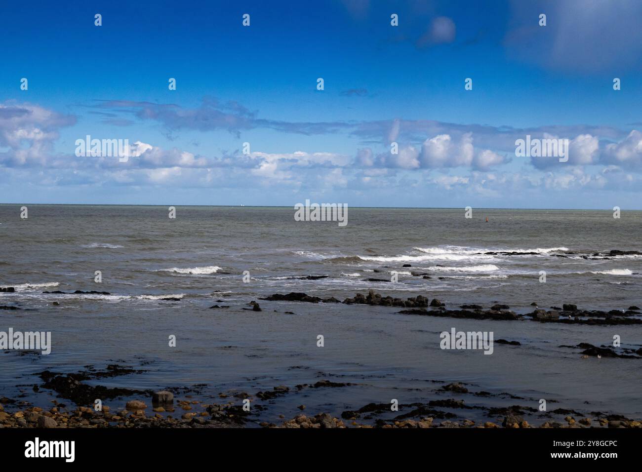 Un orizzonte separato dal cielo e dall'acqua. Le onde colpiscono le rocce. Foto Stock