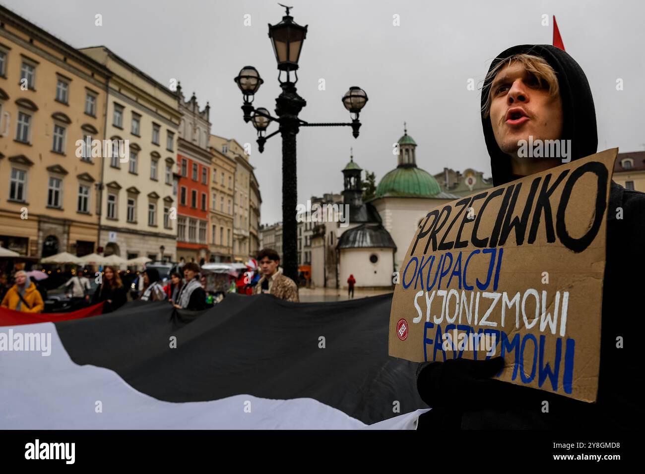 Un uomo partecipa a una protesta a sostegno della Palestina e contro le azioni di guerra israeliane nella Striscia di Gaza, in Cisgiordania e in Libano nella piazza principale della città vecchia di Cracovia. Si vedono bandiere della Palestina e cartelli pro-Palestina. Foto Stock