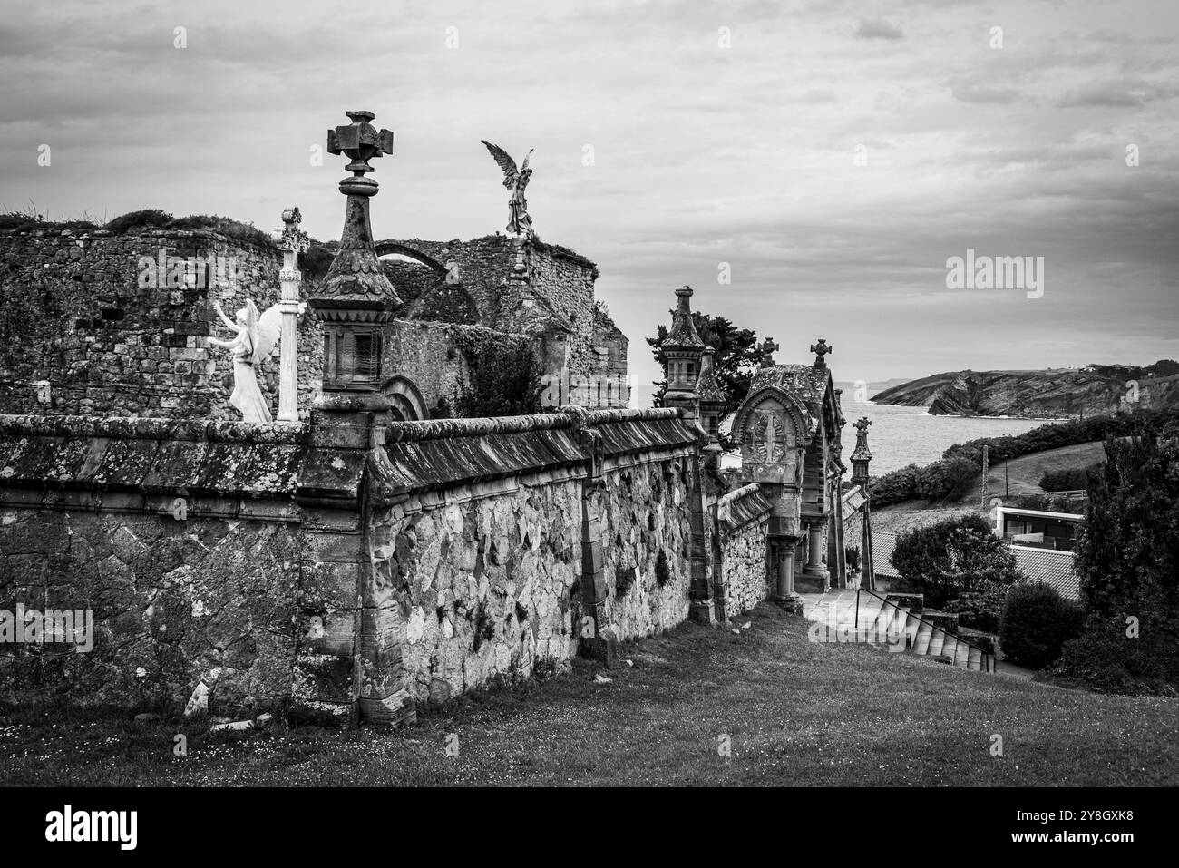 Tranquillo e storico cimitero in pietra con sculture intricate e statue di angelo che si affacciano sull'oceano, situato a Comillas, sull'oceano Atlantico Foto Stock