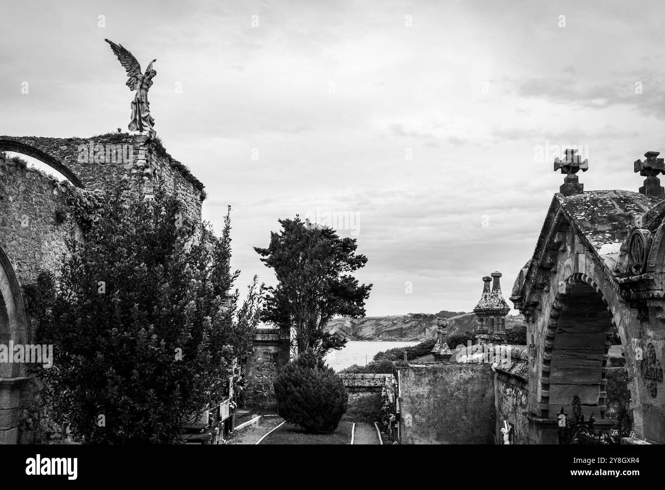 Dettagli dell'antico cimitero storico in pietra di Comillas, una statua d'angelo che si affaccia sull'oceano, Cantabria, Spagna Foto Stock