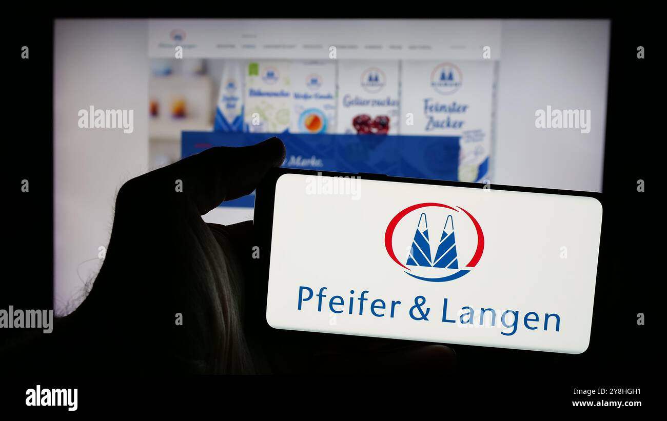 Persona che possiede uno smartphone con logo della società tedesca Pfeifer Langen GmbH Co. KG sullo schermo di fronte al sito Web. Mettere a fuoco il display del telefono. Foto Stock
