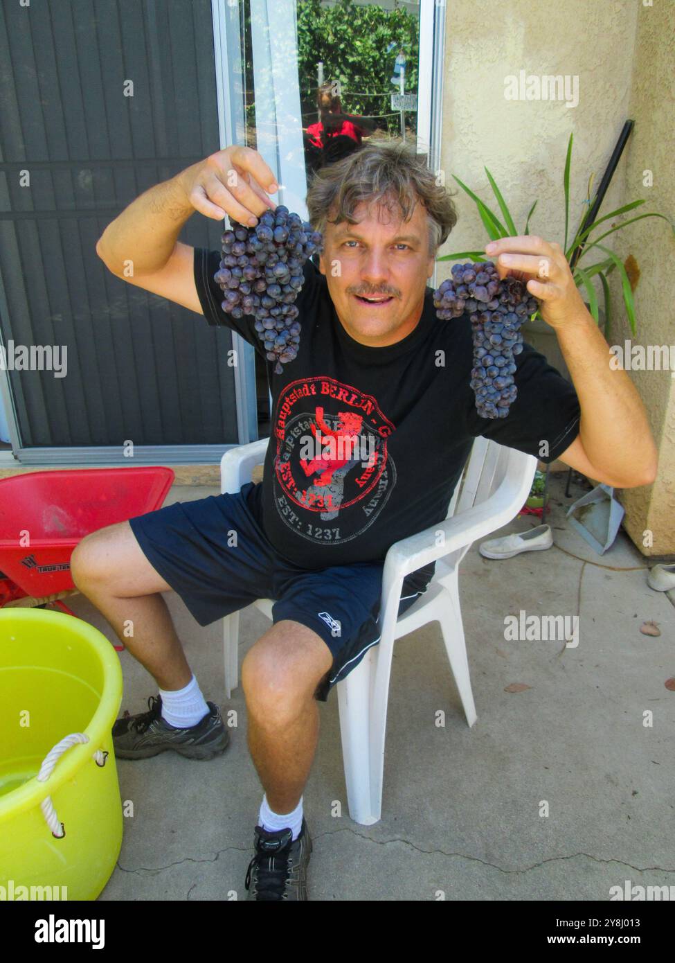 Un uomo che produce vino dalla sua uva coltivata in casa. Foto Stock